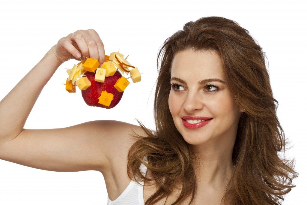 woman holding an apple and cheese cubes