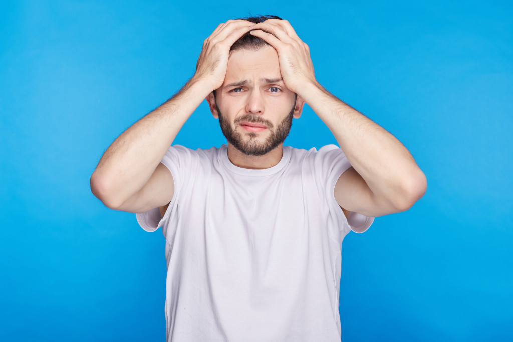 Man in white shirt holding his head