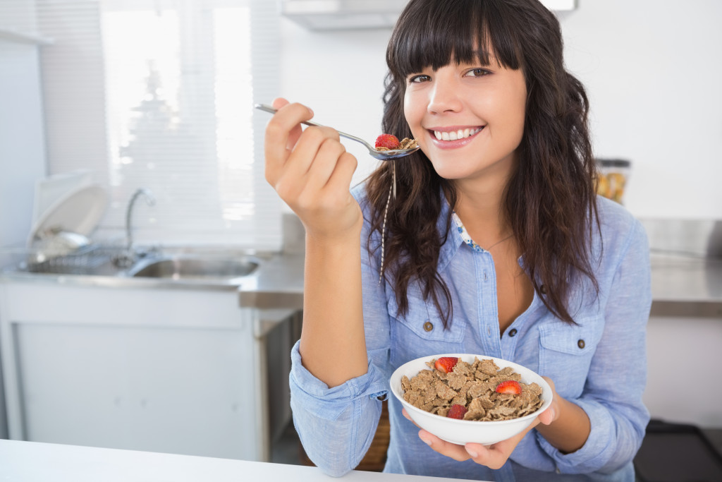 Beautiful young woman eating bowl of cereal 