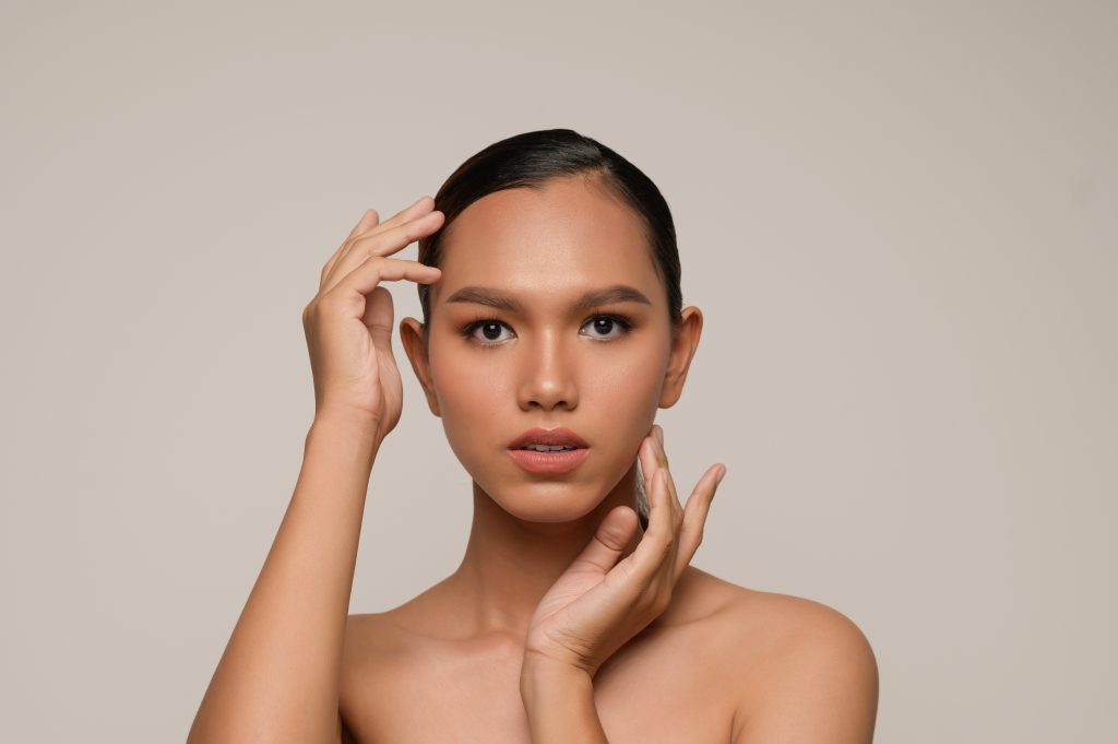 woman posing with lightly bent fingers gently touching her forehead and jaw